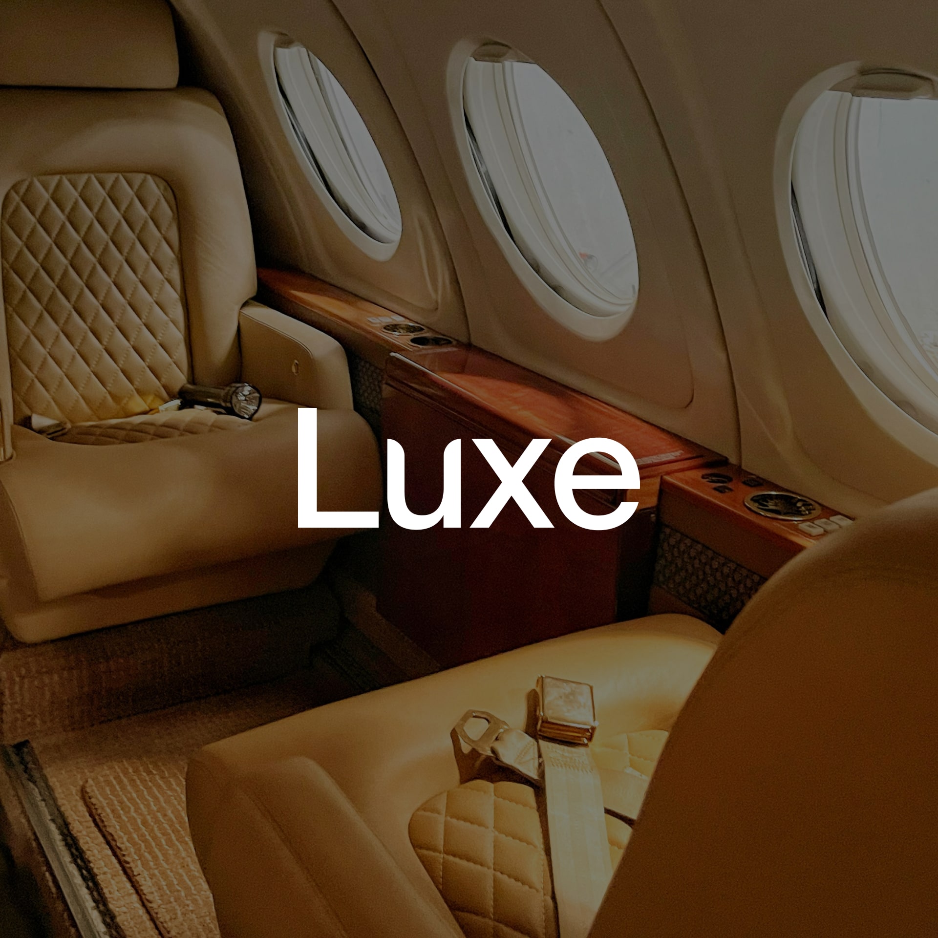 Interior of a luxury private jet with quilted leather seats and wood trim.