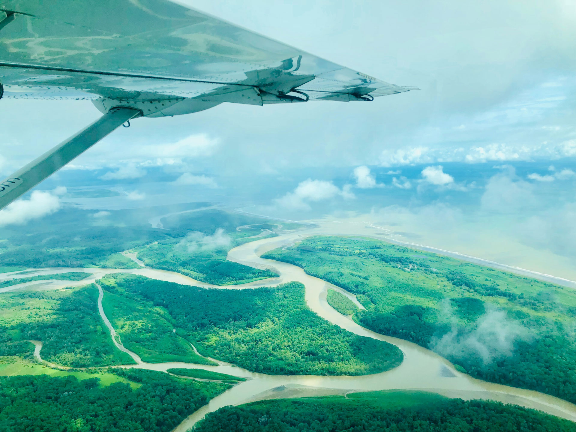 Aerial view from a small aircraft over the lush green mangroves and winding rivers of Costa Rica’s tropical landscape, with the wing of the plane visible in the frame.